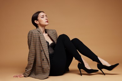 Photo of Full-length portrait of beautiful woman in stylish outfit on beige background