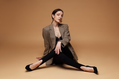 Photo of Full-length portrait of beautiful woman in stylish outfit on beige background