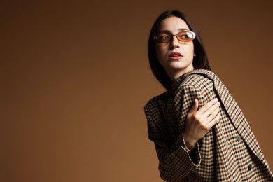 Photo of Portrait of beautiful woman in stylish outfit on brown background, space for text