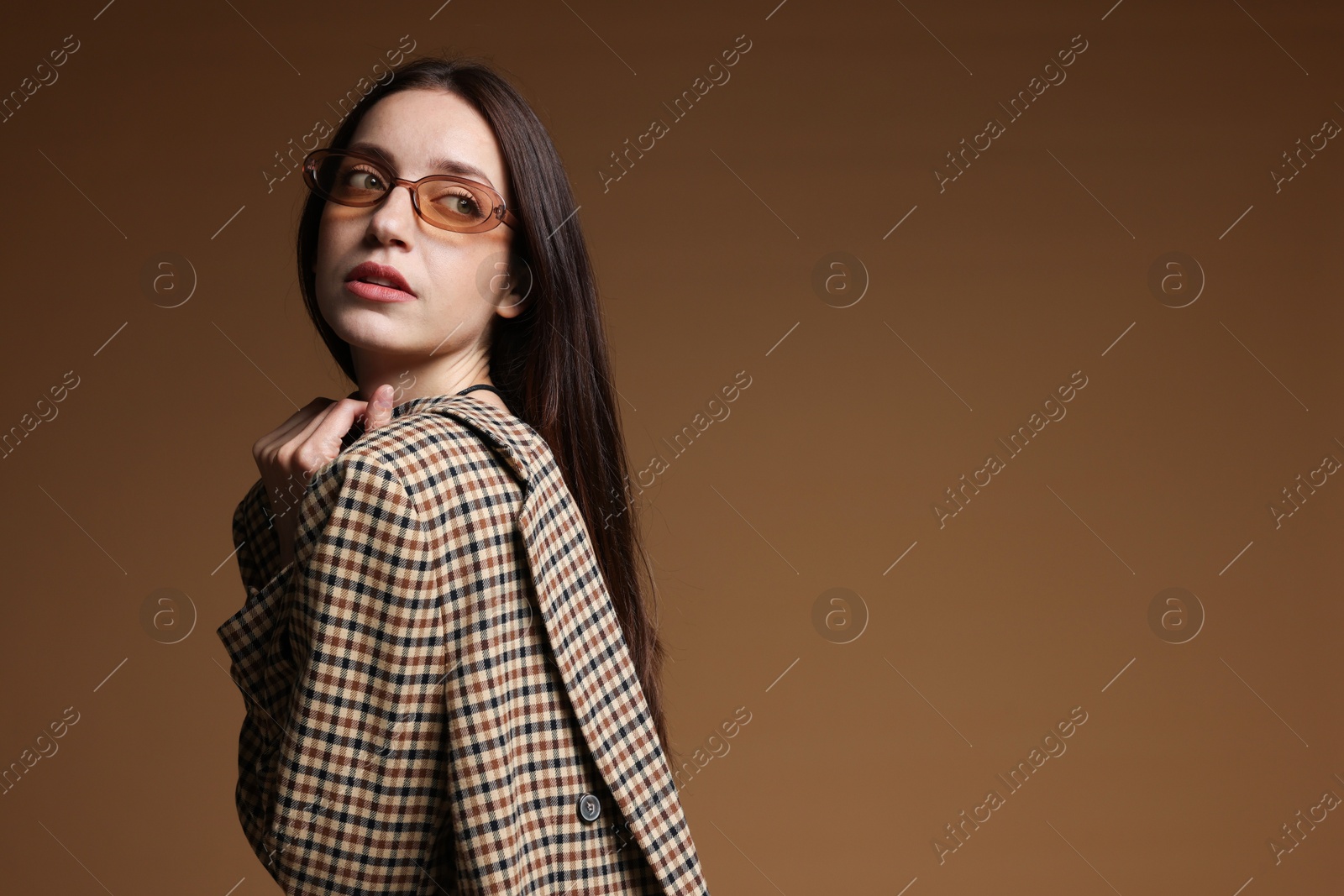 Photo of Portrait of beautiful woman in stylish outfit on brown background, space for text