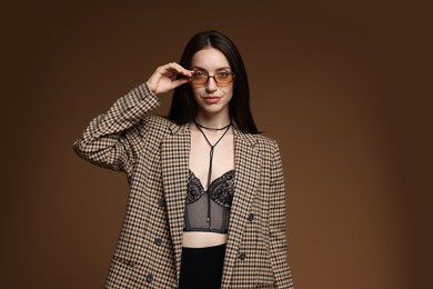 Photo of Portrait of beautiful woman in stylish outfit on brown background