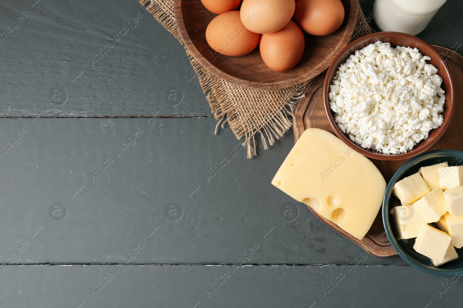 Photo of Different dairy products and eggs on grey wooden table, flat lay. Space for text