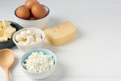 Photo of Different dairy products and eggs on white wooden table, closeup. Space for text