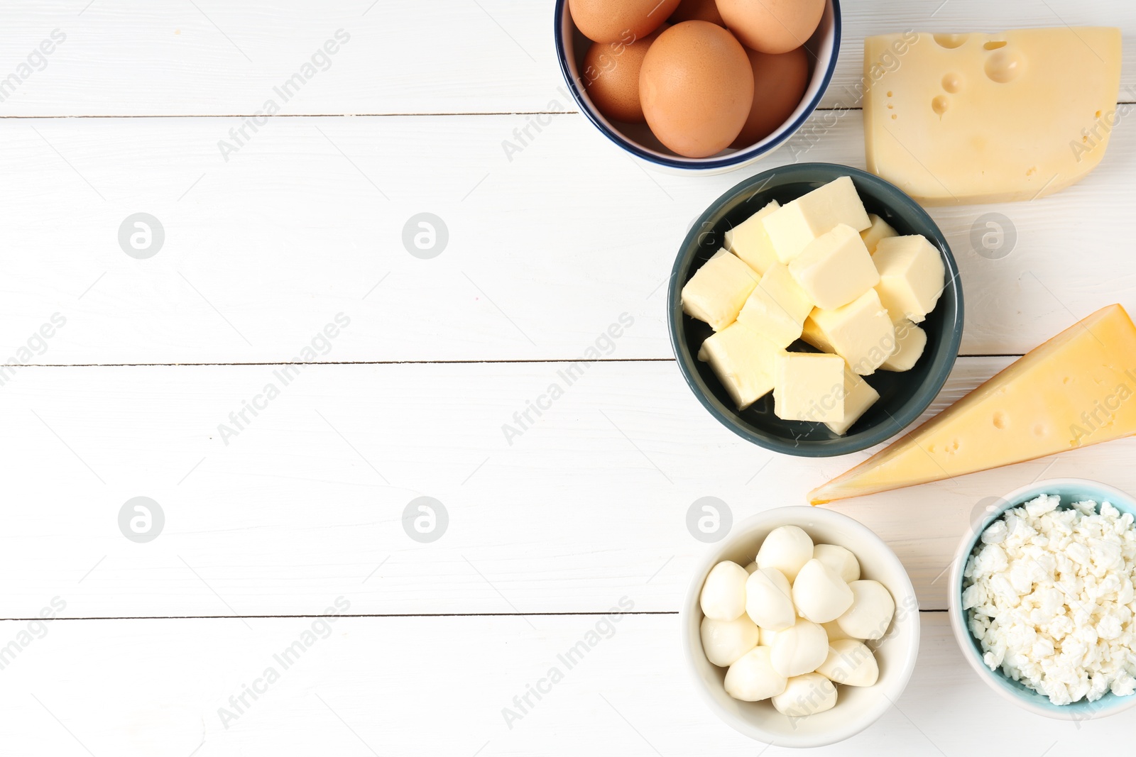 Photo of Different dairy products and eggs on white wooden table, flat lay. Space for text