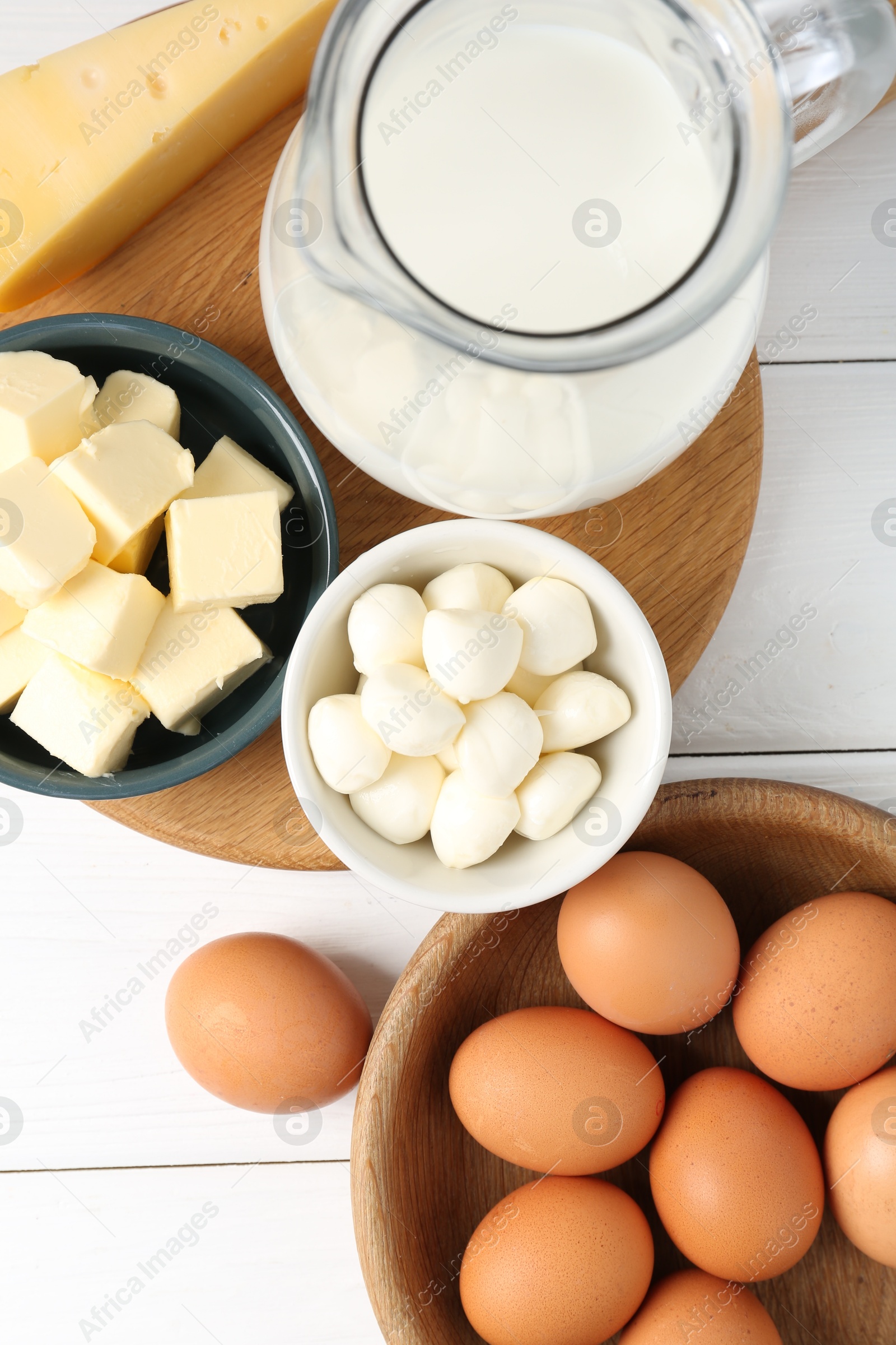 Photo of Different dairy products and eggs on white wooden table, flat lay