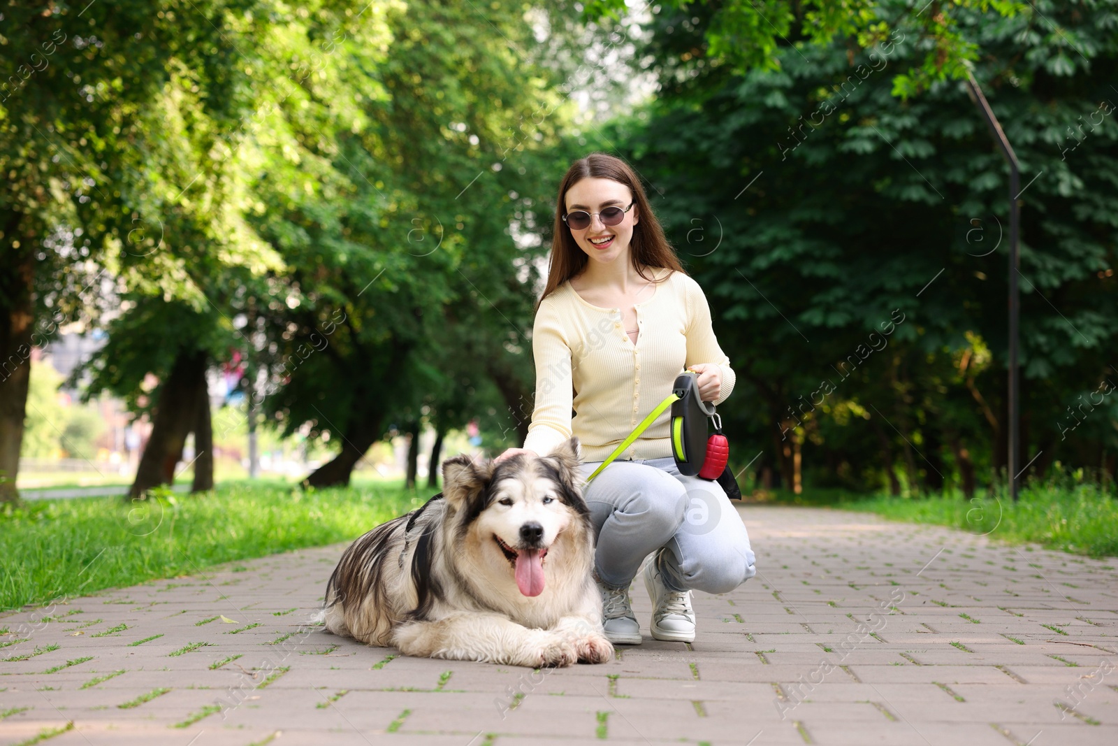 Photo of Happy woman with her cute Alaskan malamute dog in park