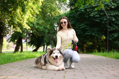 Photo of Happy woman with her cute Alaskan malamute dog in park