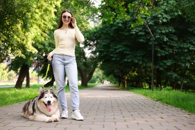 Photo of Happy woman with her cute Alaskan malamute dog in park. Space for text