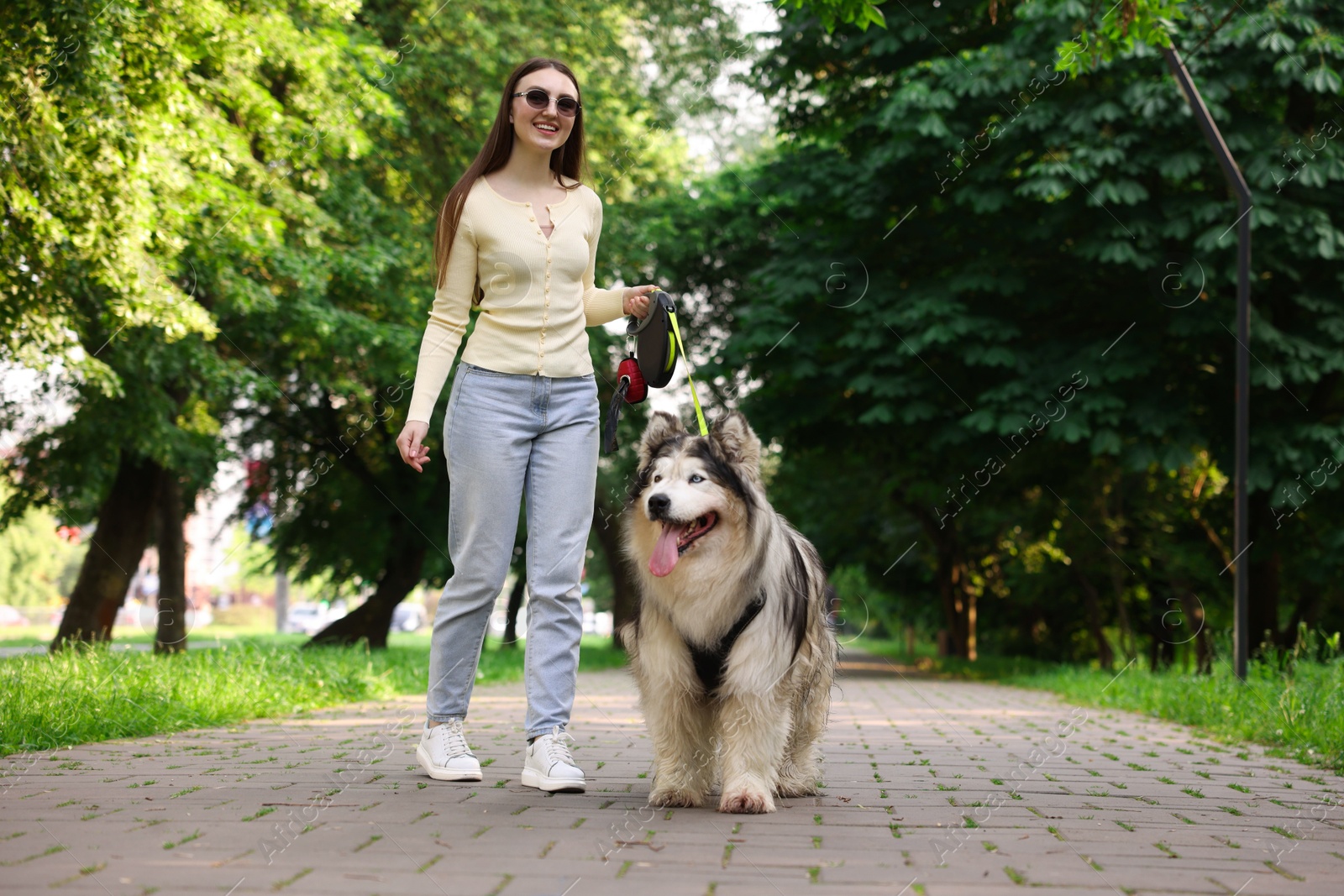 Photo of Happy woman with her cute Alaskan malamute dog in park, low angle view