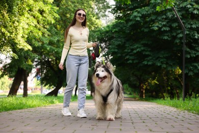 Photo of Happy woman with her cute Alaskan malamute dog in park, low angle view