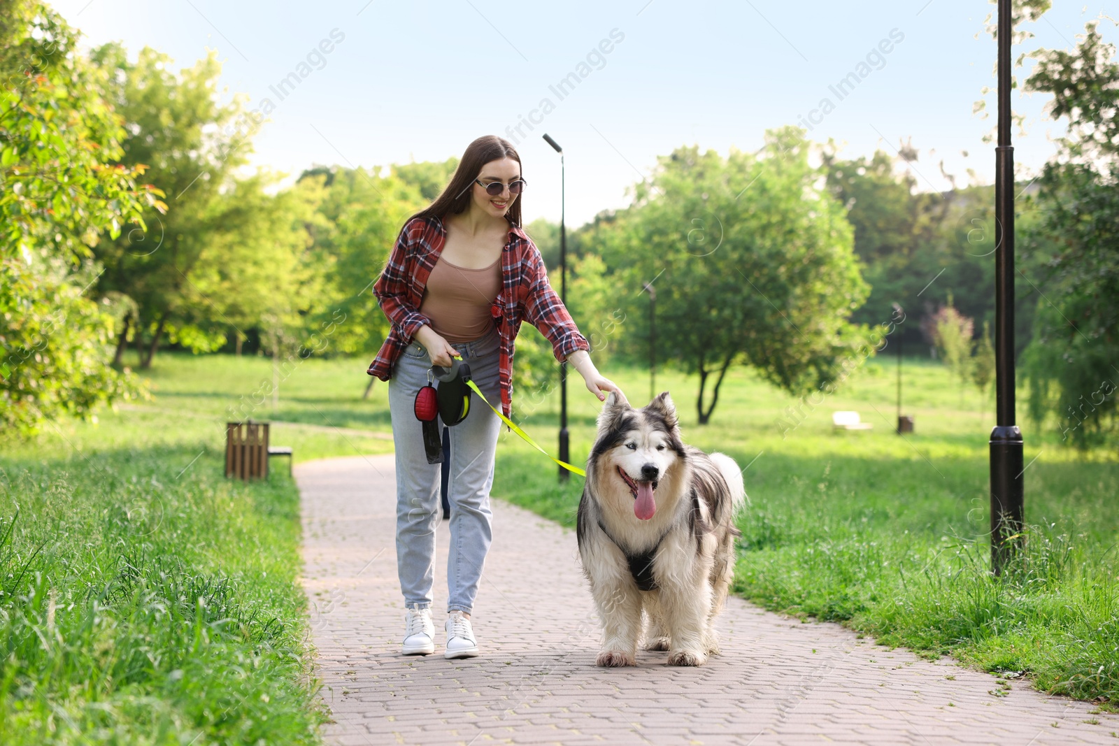 Photo of Happy woman walking with her cute Alaskan malamute dog in park