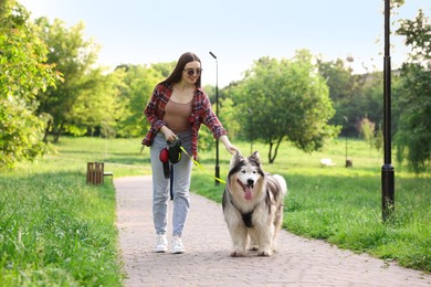 Photo of Happy woman walking with her cute Alaskan malamute dog in park