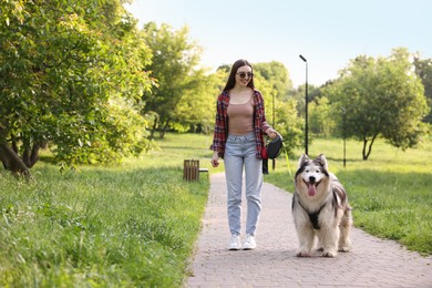 Photo of Happy woman walking with her cute Alaskan malamute dog in park