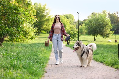 Photo of Happy woman walking with her cute Alaskan malamute dog in park