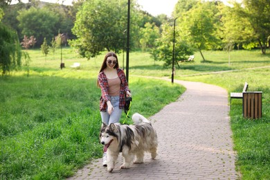 Photo of Happy woman walking with her cute Alaskan malamute dog in park