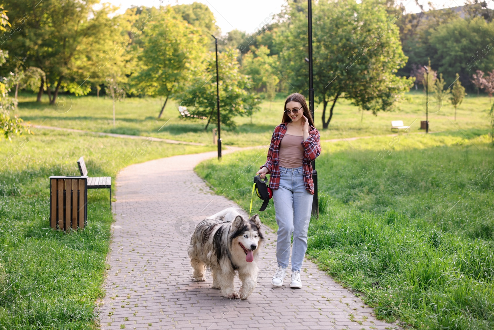 Photo of Happy woman walking with her cute Alaskan malamute dog in park