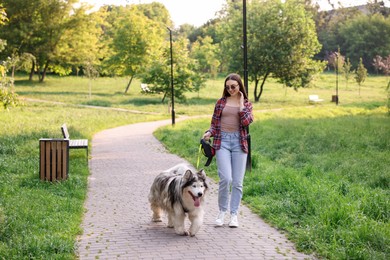Photo of Happy woman walking with her cute Alaskan malamute dog in park