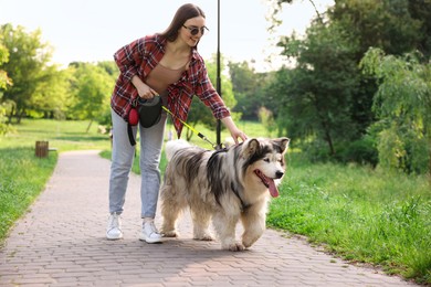 Photo of Happy woman walking with her cute Alaskan malamute dog in park