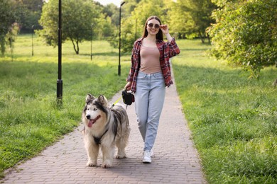 Photo of Happy woman walking with her cute Alaskan malamute dog in park