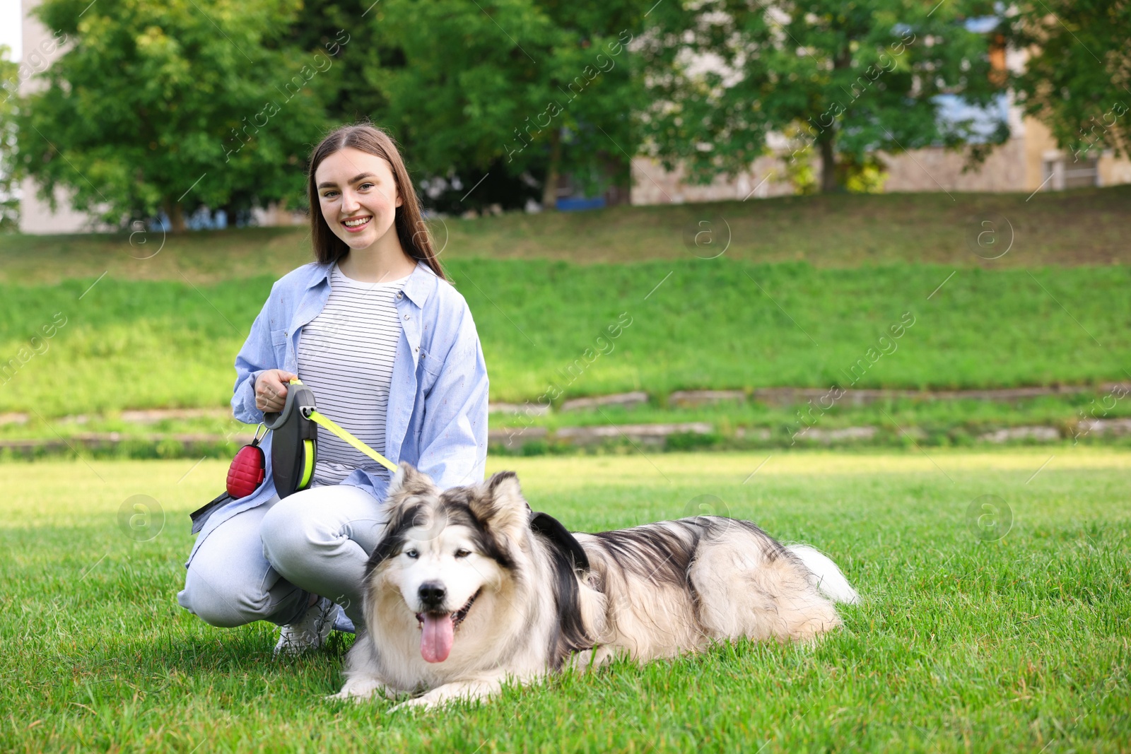 Photo of Happy woman with her cute Alaskan malamute dog on green grass outdoors