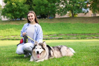 Photo of Happy woman with her cute Alaskan malamute dog on green grass outdoors