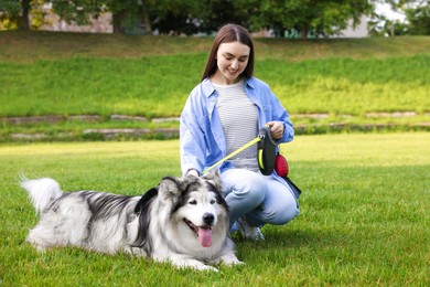 Photo of Happy woman with her cute Alaskan malamute dog on green grass outdoors