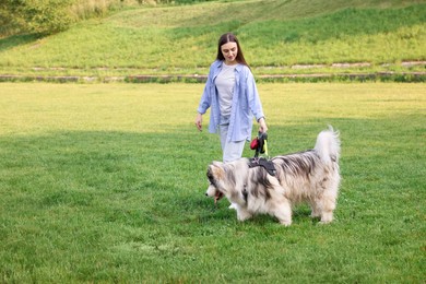Photo of Happy woman walking with her cute Alaskan malamute dog on green grass outdoors