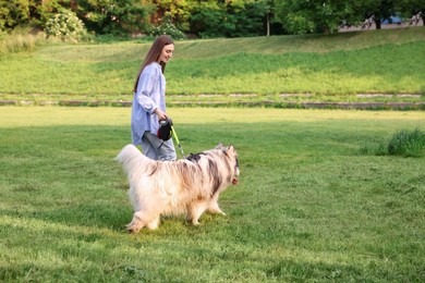Photo of Happy woman walking with her cute Alaskan malamute dog on green grass outdoors