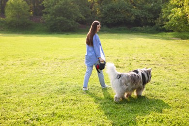 Photo of Smiling woman walking with her cute Alaskan malamute dog on green grass outdoors in morning