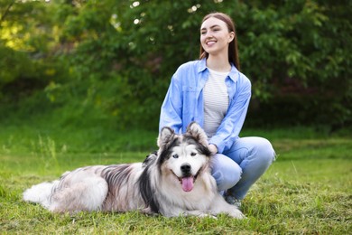 Photo of Happy woman with her cute Alaskan malamute dog on green grass outdoors