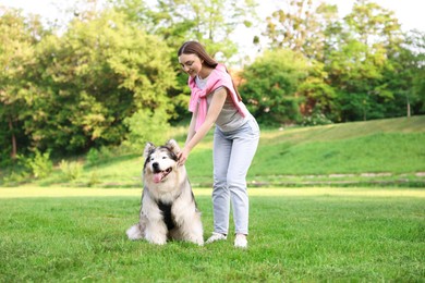 Photo of Smiling woman with her cute Alaskan malamute dog on green grass outdoors