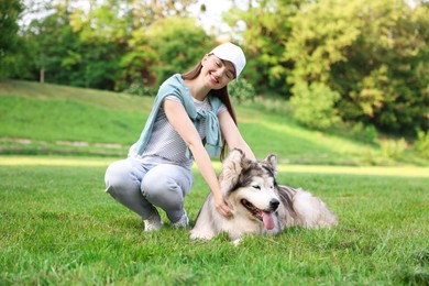 Photo of Smiling woman with her cute Alaskan malamute dog on green grass outdoors