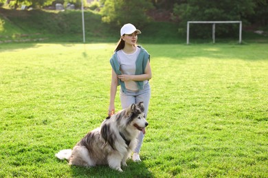 Photo of Woman with her cute Alaskan malamute dog on green grass outdoors in morning