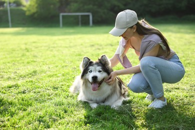 Photo of Woman with her cute Alaskan malamute dog on green grass outdoors in morning. Space for text