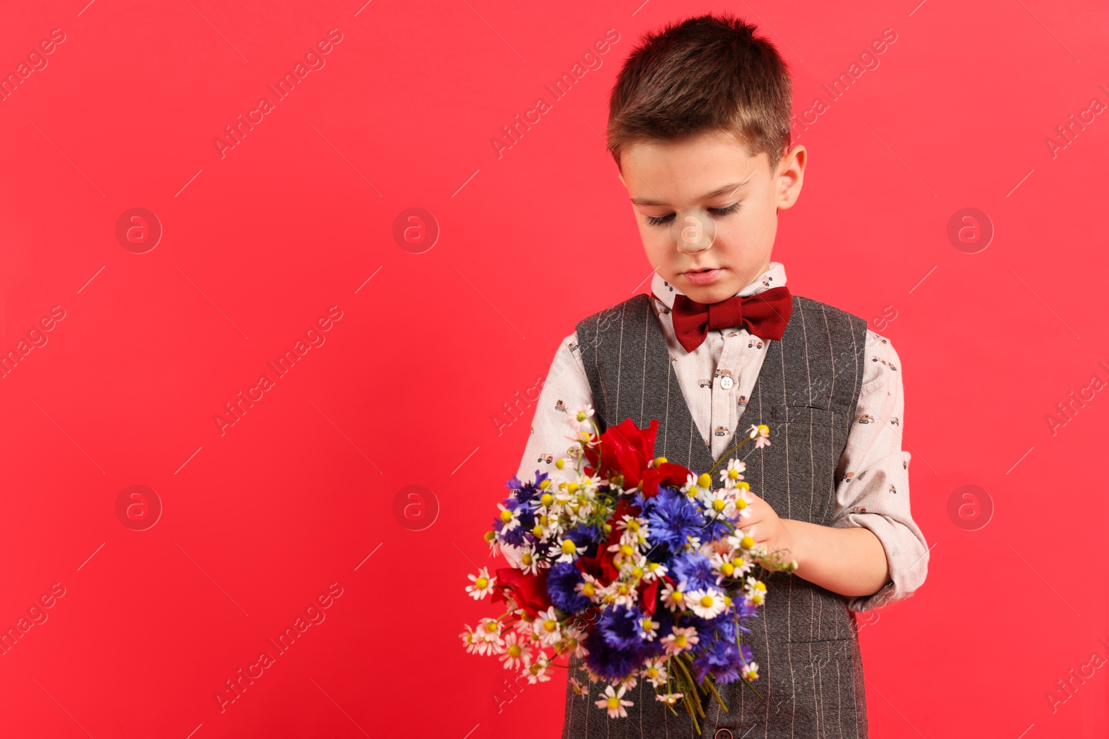 Photo of Cute little boy with bouquet of beautiful flowers on red background. Space for text