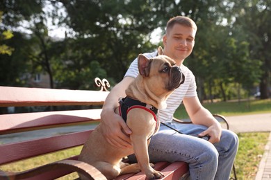 Photo of Happy man with his cute French bulldog on bench in park