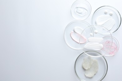 Photo of Different cosmetic products in Petri dishes on white background, flat lay. Space for text
