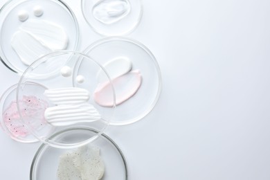 Photo of Different cosmetic products in Petri dishes on white background, flat lay. Space for text
