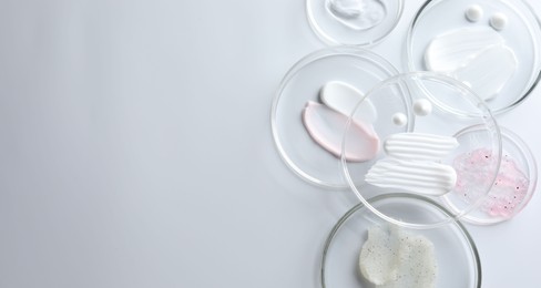 Photo of Different cosmetic products in Petri dishes on white background, flat lay. Space for text