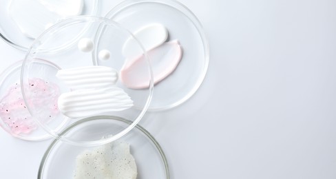 Photo of Different cosmetic products in Petri dishes on white background, flat lay. Space for text
