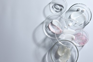 Photo of Different cosmetic products in Petri dishes on white background, flat lay. Space for text
