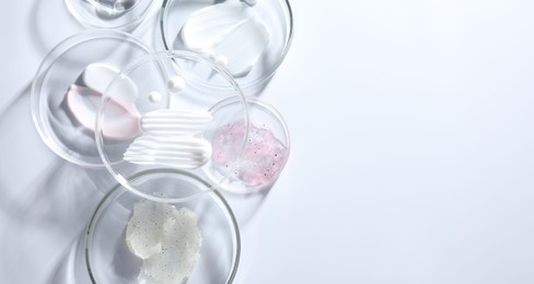 Photo of Different cosmetic products in Petri dishes on white background, flat lay. Space for text