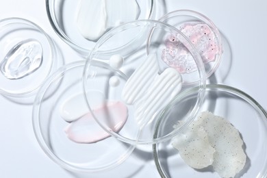 Photo of Different cosmetic products in Petri dishes on white background, flat lay