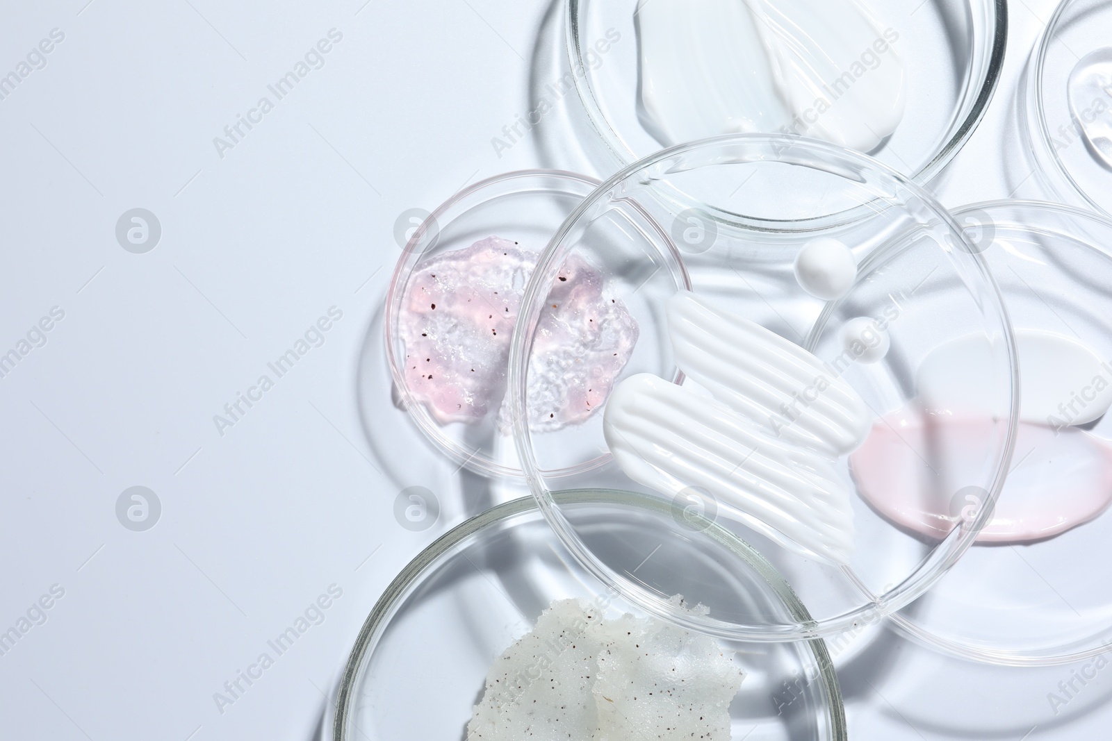 Different cosmetic products in Petri dishes on white background, flat lay. Space for text Photo of Different cosmetic products in Petri dishes on white background, flat lay. Space for text