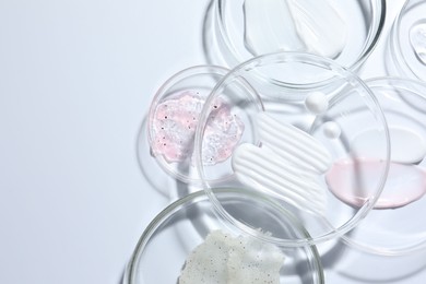 Photo of Different cosmetic products in Petri dishes on white background, flat lay. Space for text