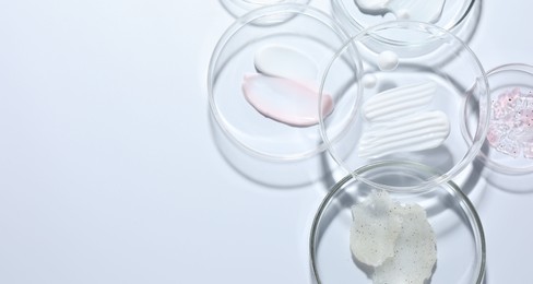 Photo of Different cosmetic products in Petri dishes on white background, flat lay. Space for text
