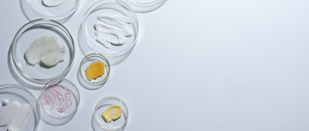 Photo of Different cosmetic products in Petri dishes on white background, flat lay. Space for text