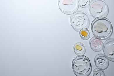 Photo of Different cosmetic products in Petri dishes on white background, flat lay. Space for text