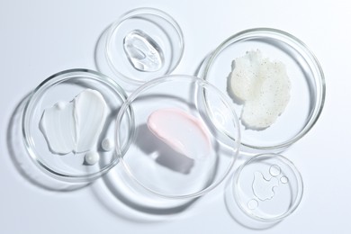Photo of Different cosmetic products in Petri dishes on white background, flat lay