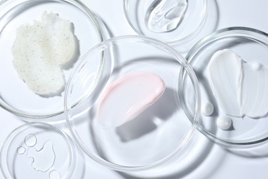 Photo of Different cosmetic products in Petri dishes on white background, closeup